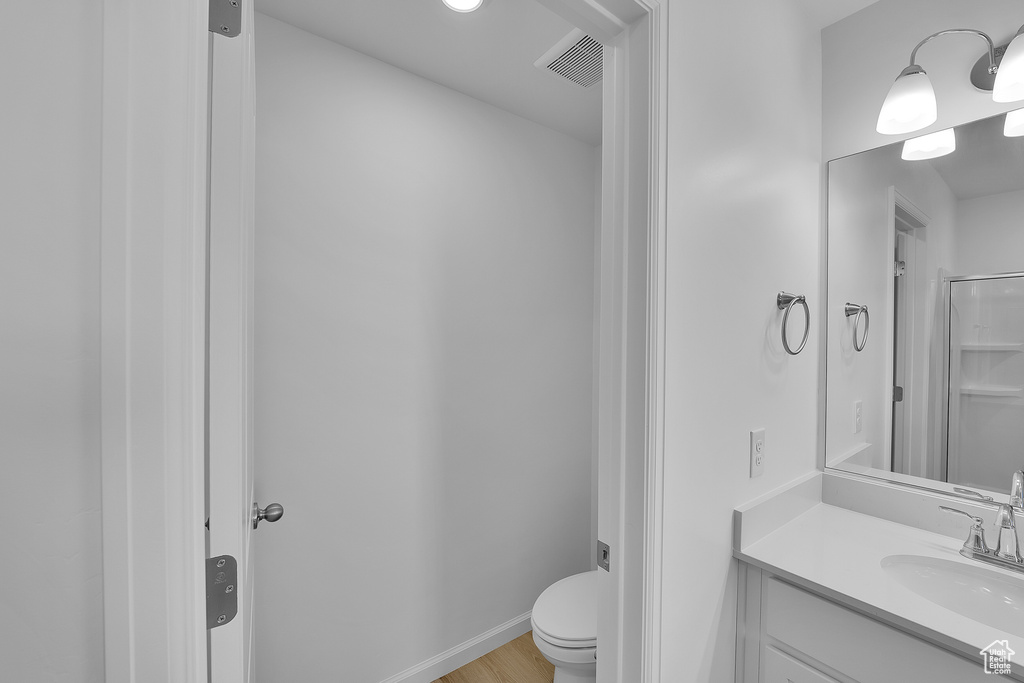 Bathroom with toilet, vanity, and wood finished floors