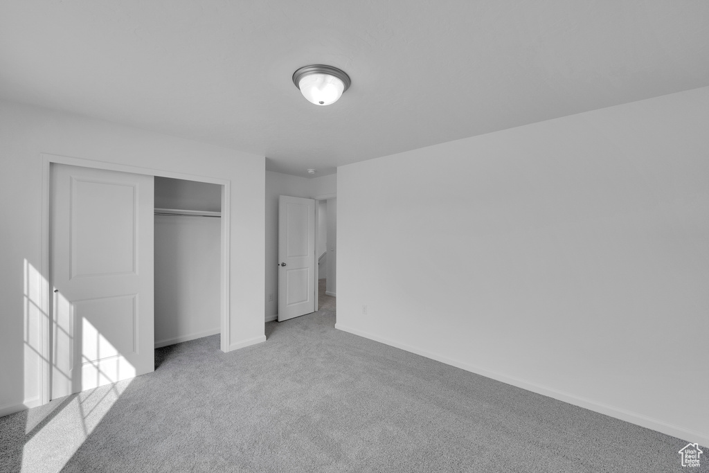 Unfurnished bedroom with carpet floors, baseboards, and a closet