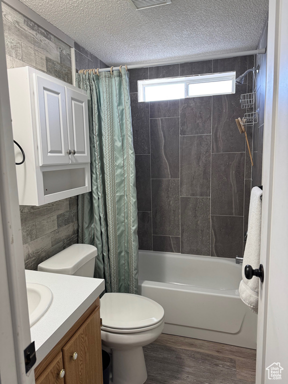 Full bathroom featuring vanity, wood-type flooring, a textured ceiling, and shower / bath combo