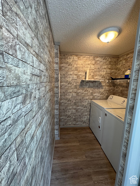 Laundry room with washer and clothes dryer, hardwood / wood-style floors, and a textured ceiling