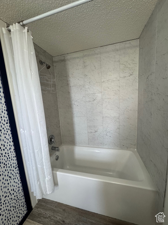 Bathroom featuring hardwood / wood-style floors, a textured ceiling, and shower / tub combo with curtain