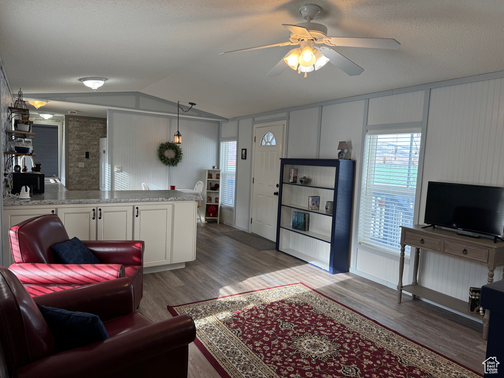 Living room featuring a textured ceiling, ceiling fan, lofted ceiling, and dark wood-type flooring