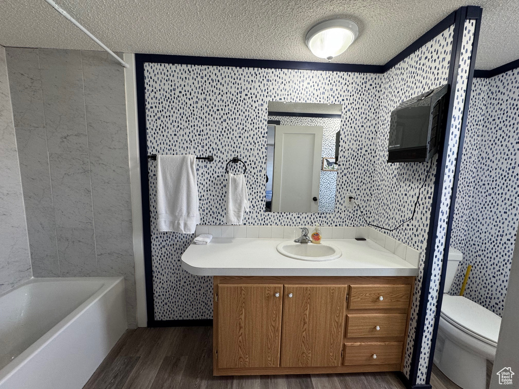 Bathroom featuring hardwood / wood-style floors, vanity, a textured ceiling, and toilet