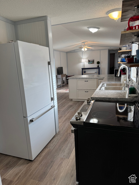 Kitchen featuring white cabinetry, black / electric stove, white fridge, light hardwood / wood-style floors, and a textured ceiling