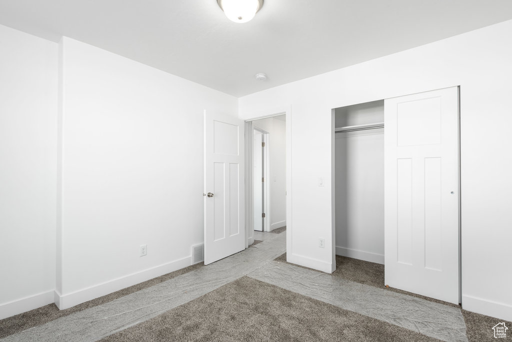 Unfurnished bedroom with light carpet and a closet