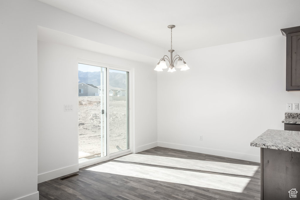 Unfurnished dining area featuring a chandelier and hardwood / wood-style floors