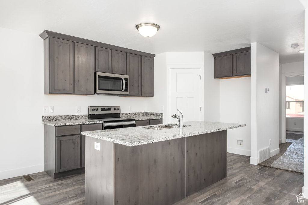 Kitchen with sink, dark brown cabinetry, stainless steel appliances, and dark wood-type flooring