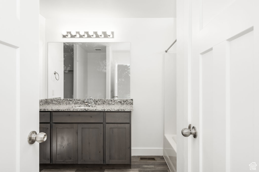 Bathroom with vanity, shower / bathtub combination, and wood-type flooring