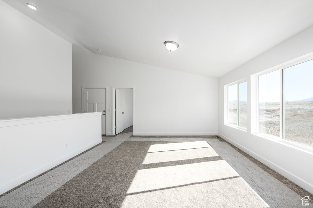 Carpeted empty room with lofted ceiling