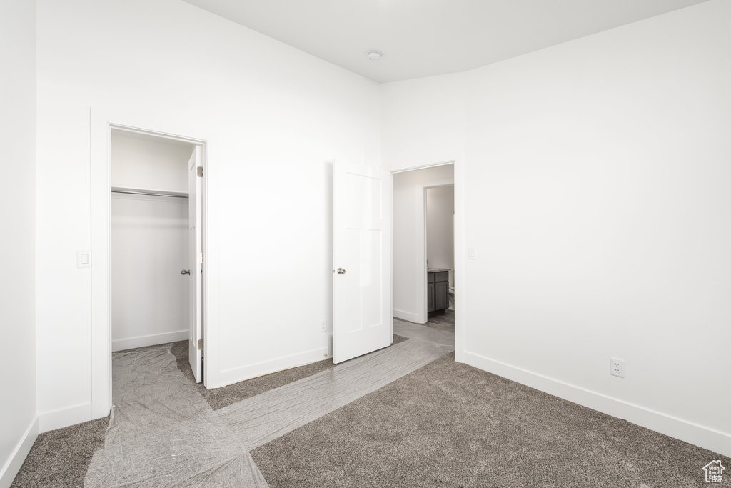 Unfurnished bedroom with a spacious closet, light carpet, and a closet