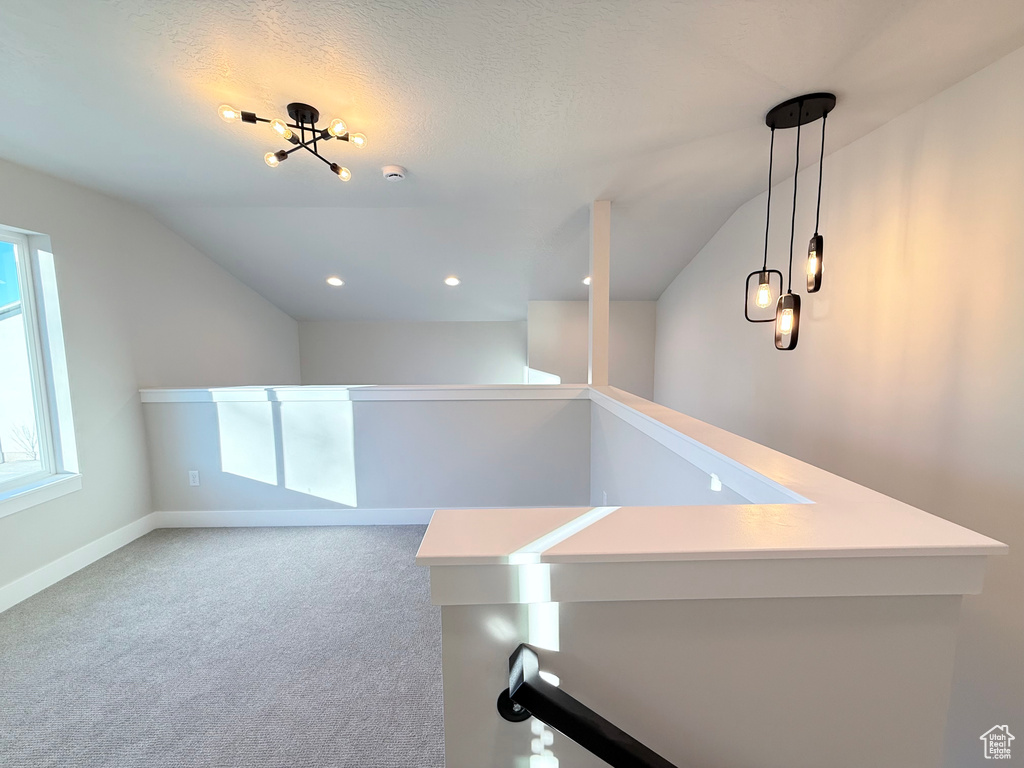 Hallway with a textured ceiling, carpet floors, and lofted ceiling