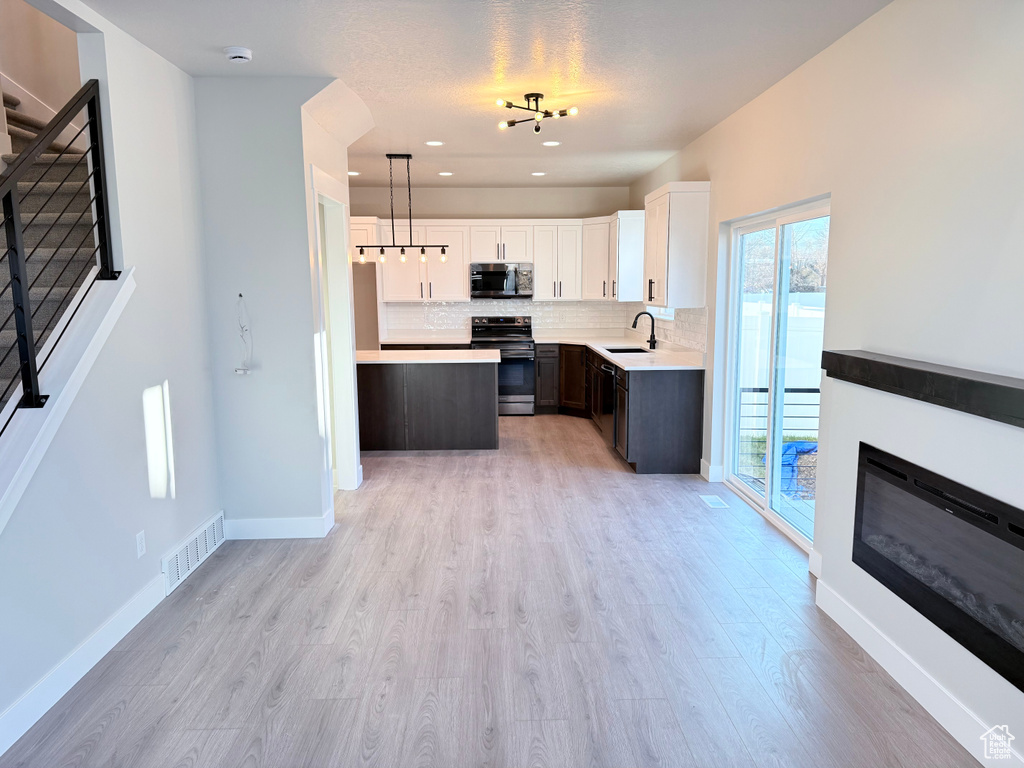 Kitchen featuring sink, hanging light fixtures, white cabinetry, dark brown cabinetry, and stainless steel appliances