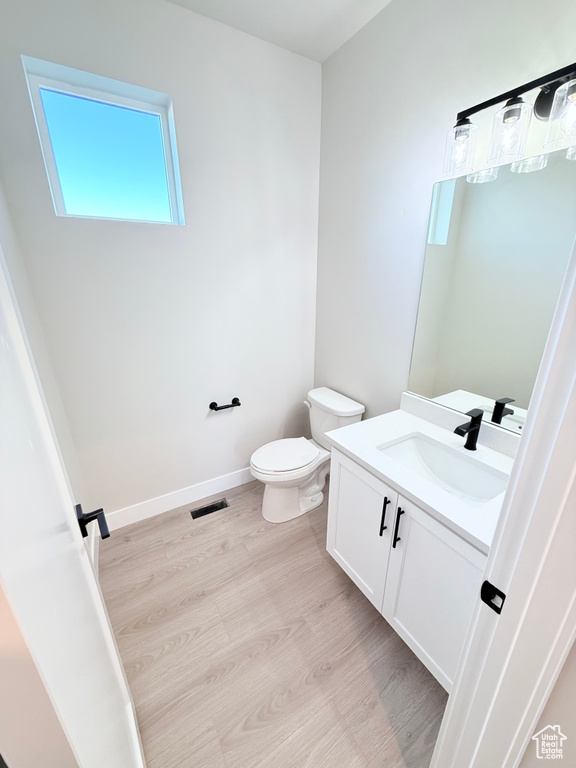 Bathroom featuring vanity, wood-type flooring, and toilet