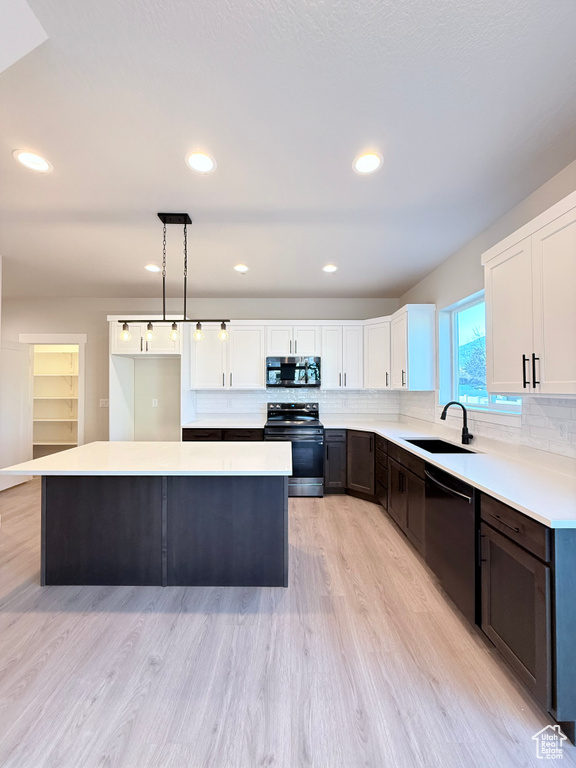 Kitchen with decorative light fixtures, sink, white cabinetry, and stainless steel appliances