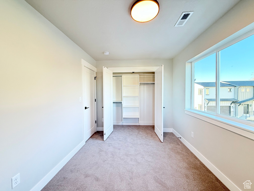 Unfurnished bedroom with light carpet and a closet