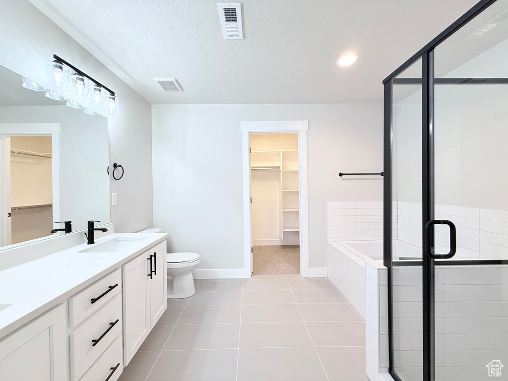 Full bathroom featuring tile patterned floors, a textured ceiling, toilet, vanity, and shower with separate bathtub