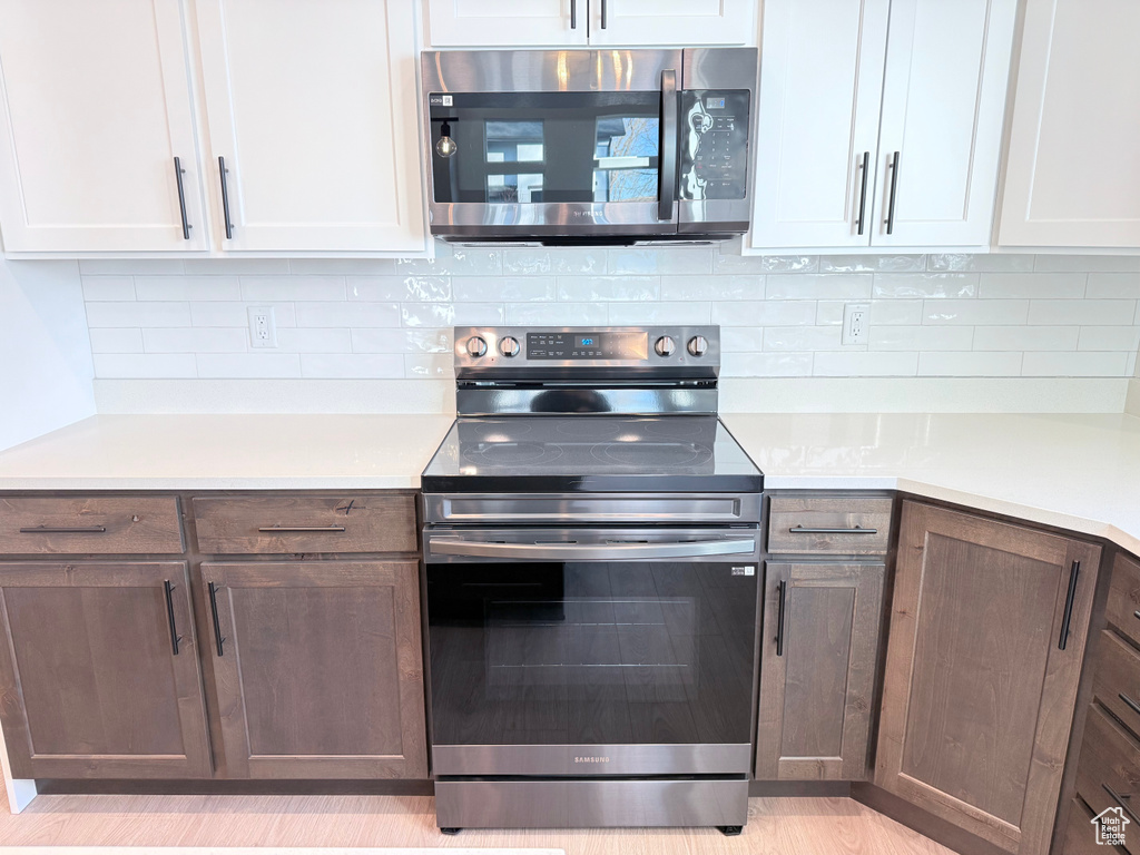 Kitchen featuring appliances with stainless steel finishes, tasteful backsplash, and white cabinetry