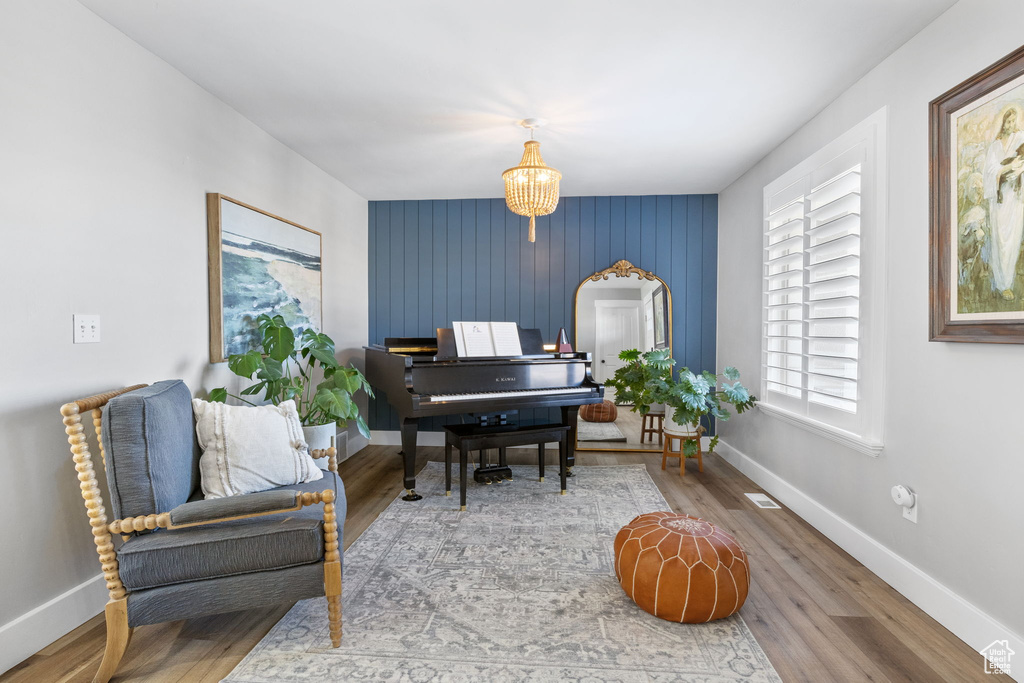 Home office with hardwood / wood-style flooring, wooden walls, and an inviting chandelier