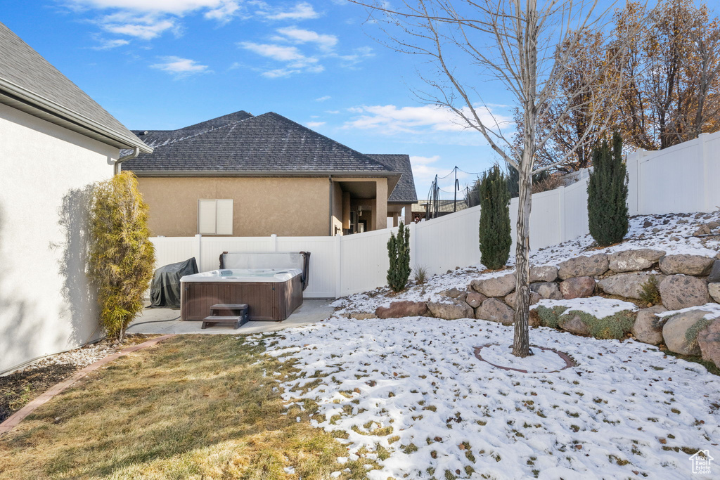 Snowy yard featuring a hot tub