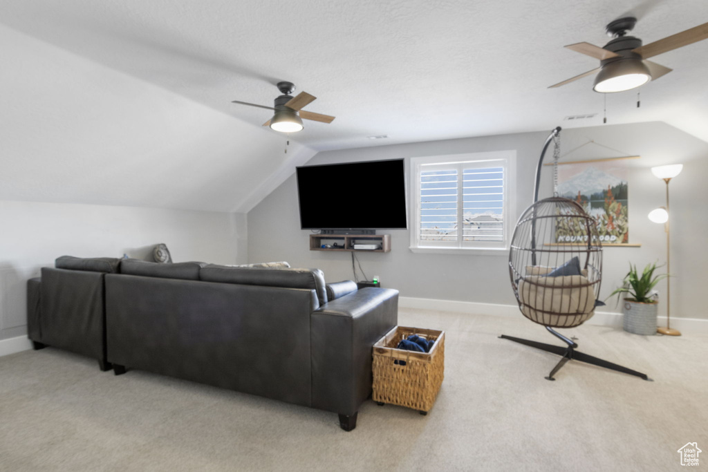 Carpeted living room featuring ceiling fan and vaulted ceiling