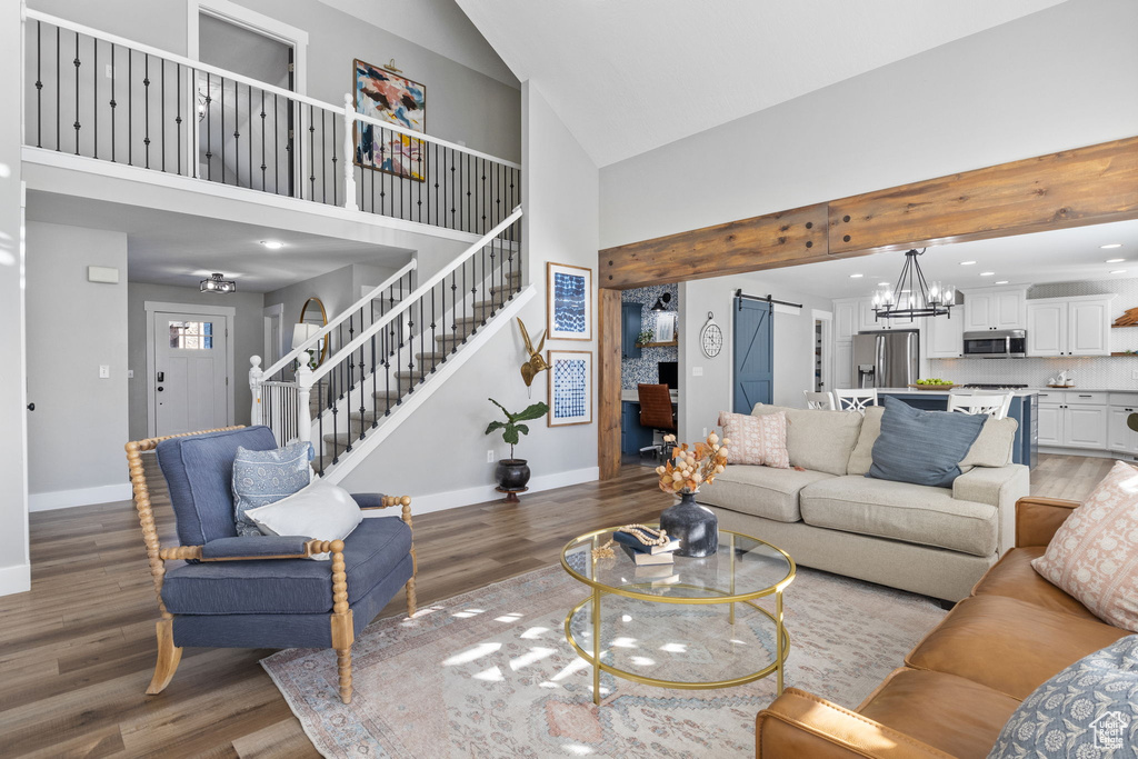 Living room with a barn door, high vaulted ceiling, and dark hardwood / wood-style floors