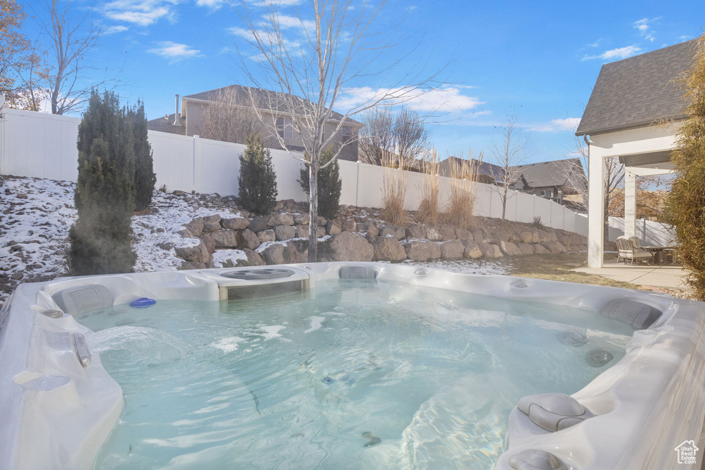 Snow covered pool featuring a hot tub