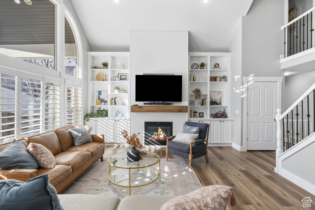 Living room with hardwood / wood-style floors, a large fireplace, and high vaulted ceiling