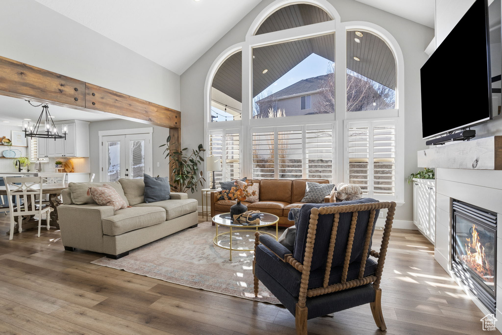 Living room with hardwood / wood-style floors, high vaulted ceiling, french doors, and a notable chandelier