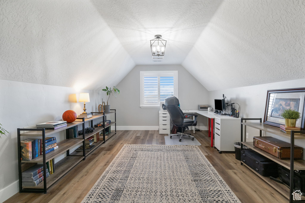 Home office with hardwood / wood-style floors, lofted ceiling, and a textured ceiling