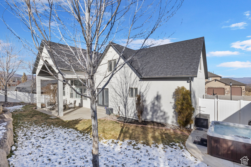 View of snowy exterior featuring a patio and a hot tub