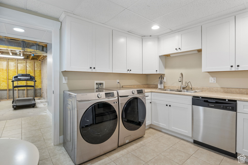 Laundry area featuring washer and clothes dryer, sink, and light tile patterned floors