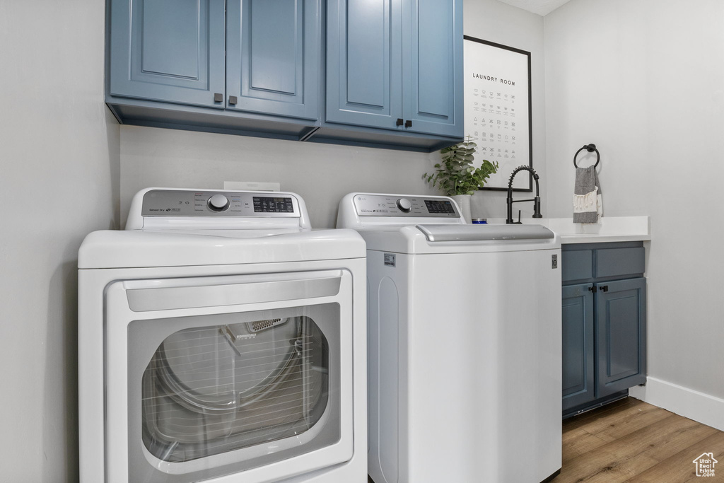 Washroom with cabinets, light hardwood / wood-style floors, and washer and clothes dryer