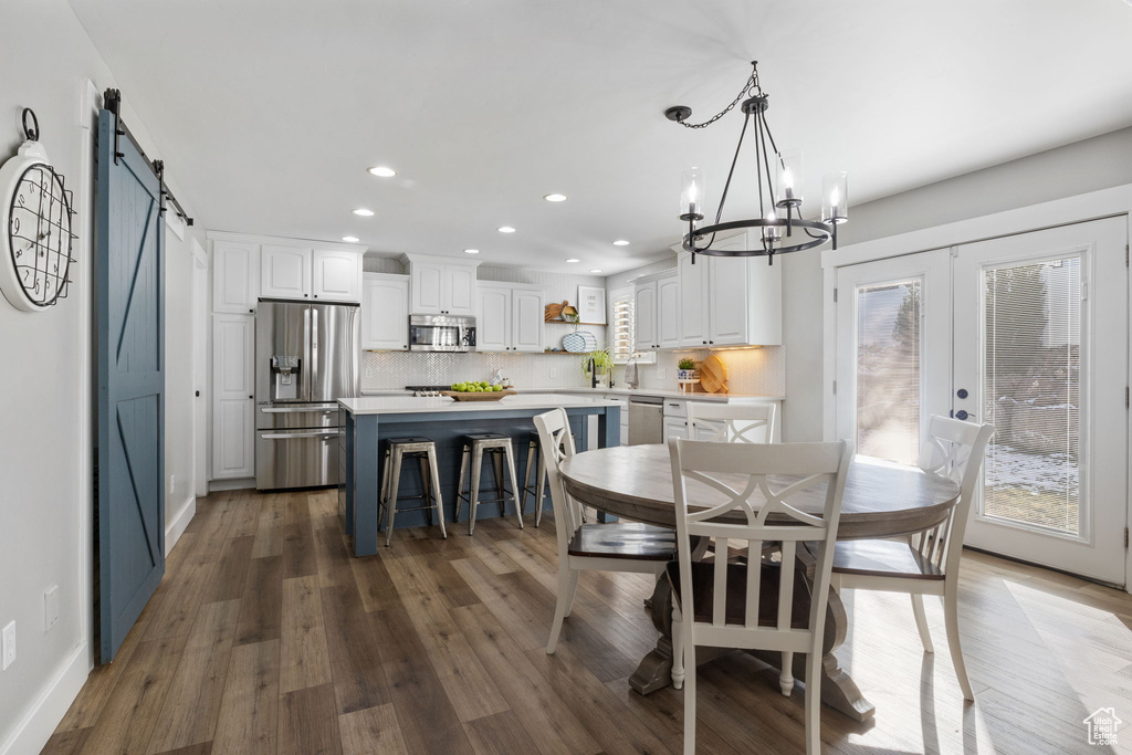 Dining area featuring french doors, sink, a barn door, hardwood / wood-style flooring, and an inviting chandelier