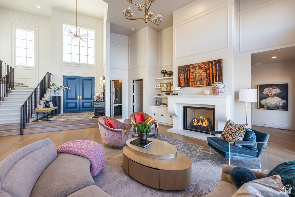 Living room featuring a towering ceiling, hardwood / wood-style flooring, and a notable chandelier