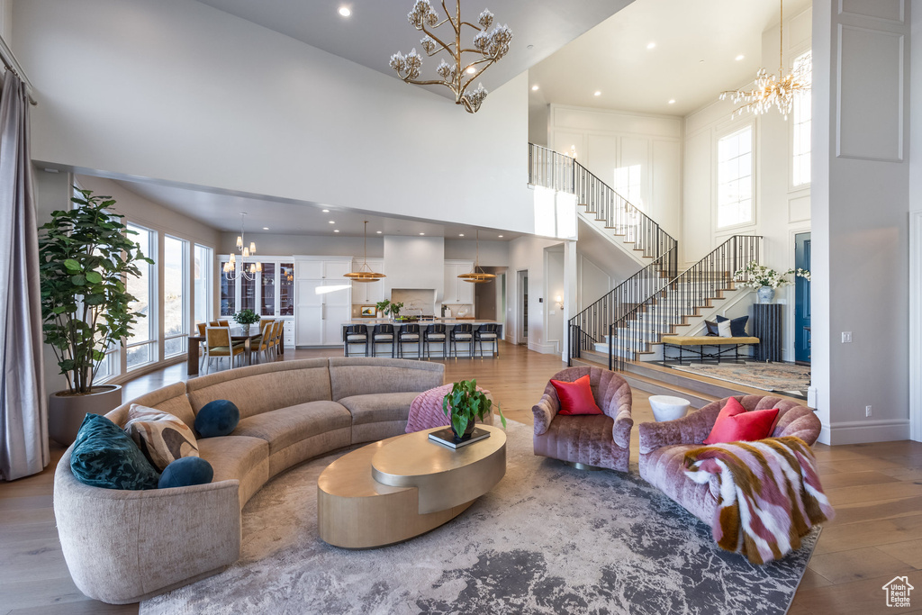 Living room featuring hardwood / wood-style floors, plenty of natural light, a notable chandelier, and a high ceiling