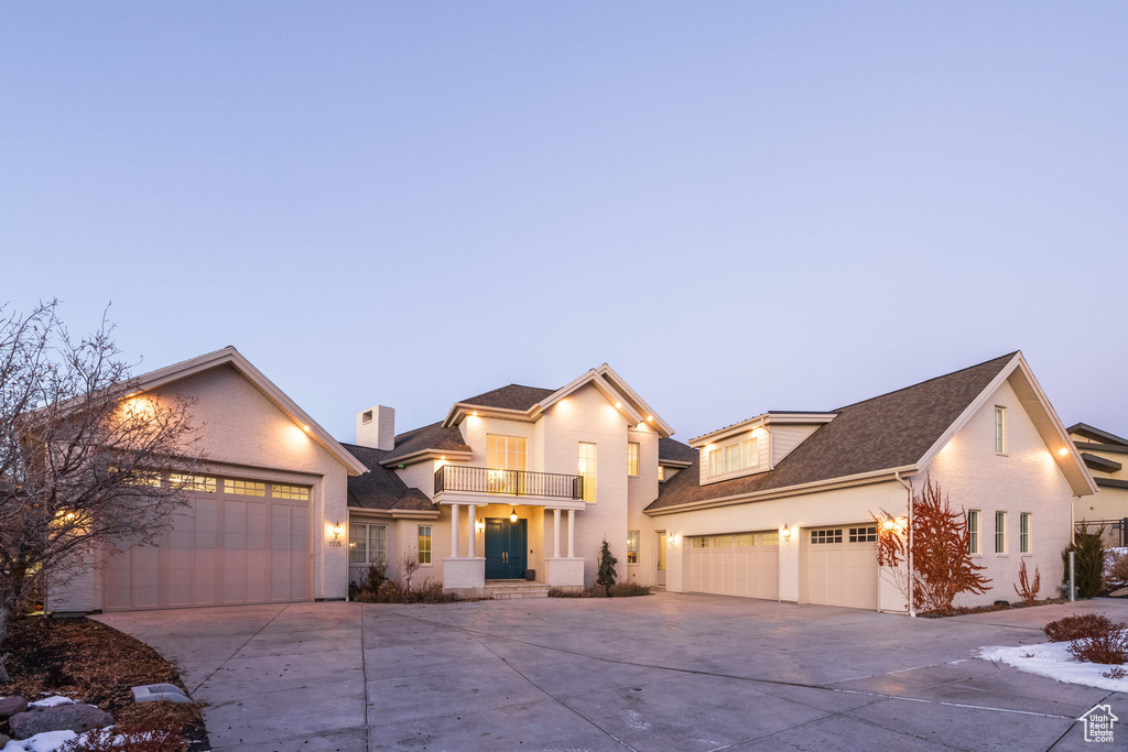View of front of property with a balcony, concrete driveway, an attached garage, and roof with shingles