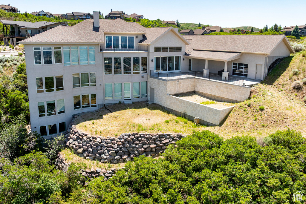 Back of house featuring a chimney, roof with shingles, a residential view, and a patio