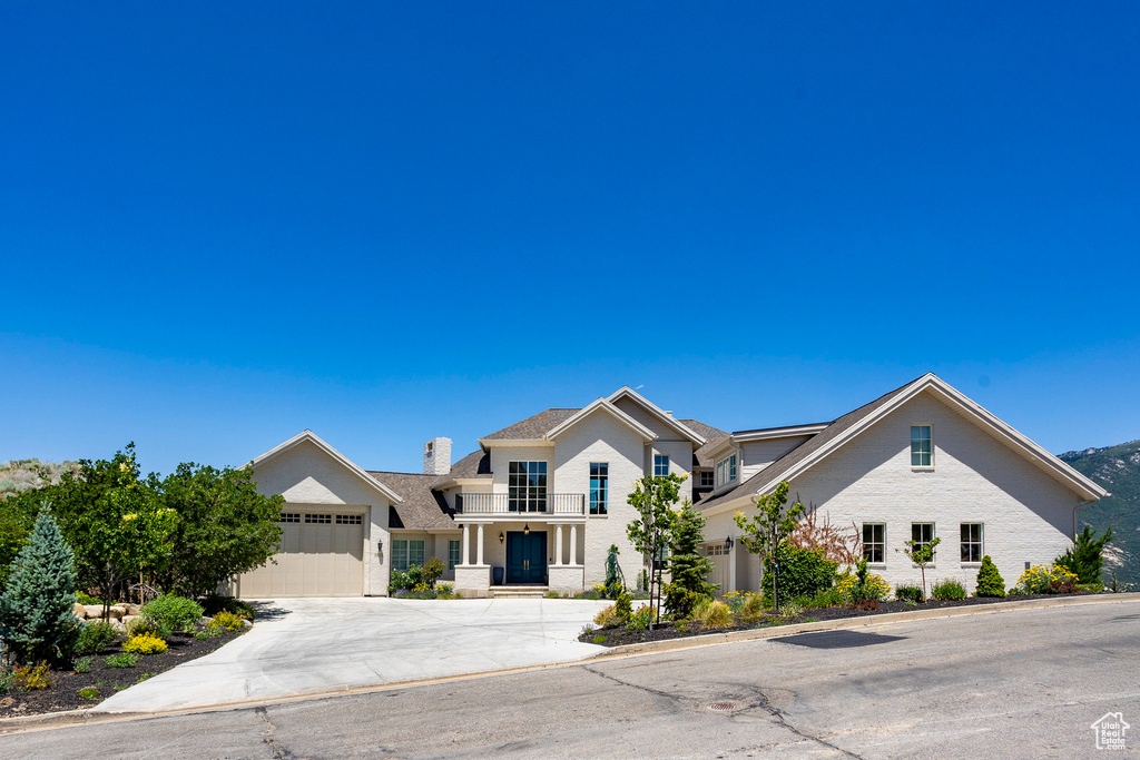 View of front facade with concrete driveway, an attached garage, a chimney, and brick siding