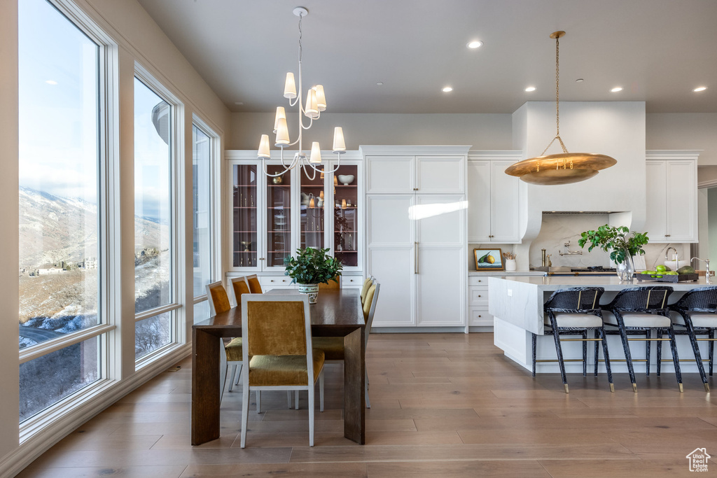 Dining space with light wood-type flooring and an inviting chandelier