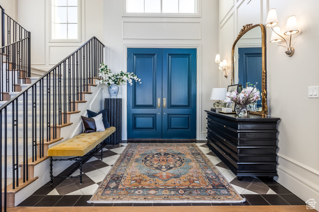Entrance foyer featuring plenty of natural light, dark tile patterned floors, and a high ceiling