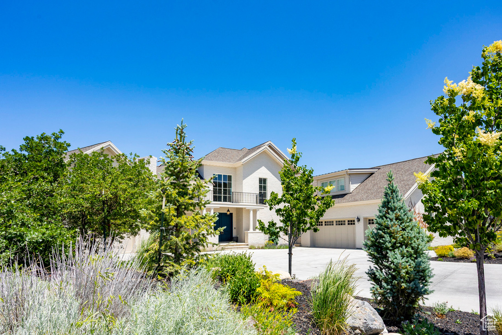 View of front of property with driveway, a balcony, and a garage