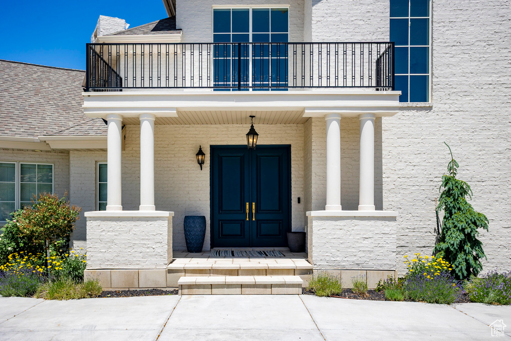 Doorway to property with a balcony, covered porch, and stone siding