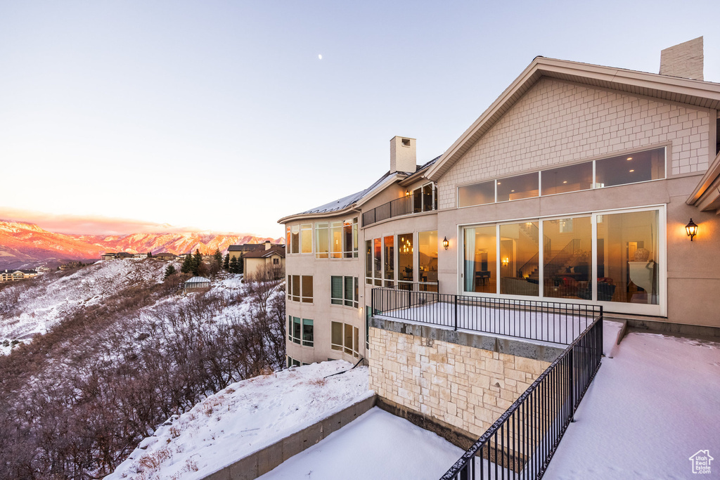 Snow covered rear of property featuring a mountain view