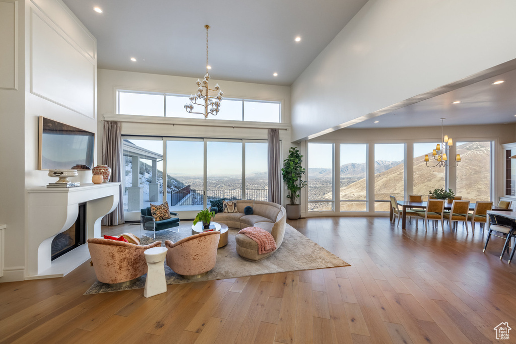 Living room featuring a mountain view, light hardwood / wood-style flooring, a towering ceiling, and an inviting chandelier