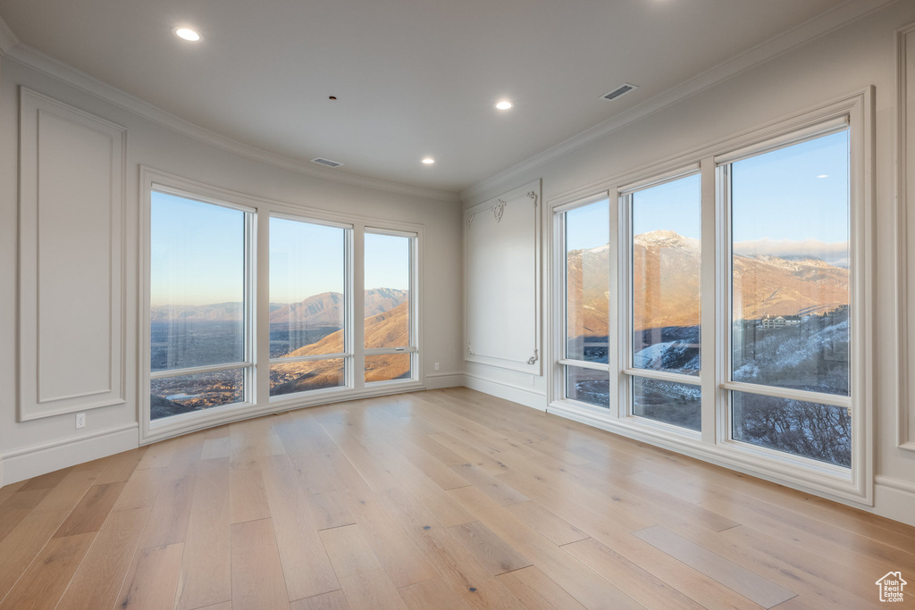 Empty room featuring a mountain view, light hardwood / wood-style floors, and ornamental molding