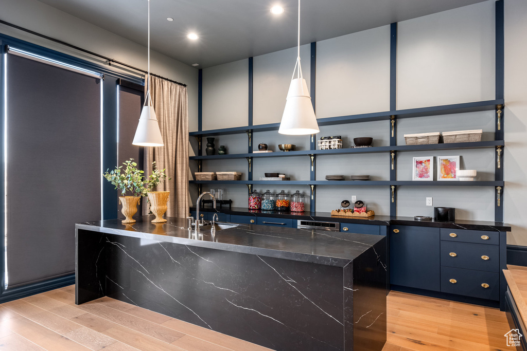 Kitchen with sink, a center island, blue cabinets, pendant lighting, and light wood-type flooring