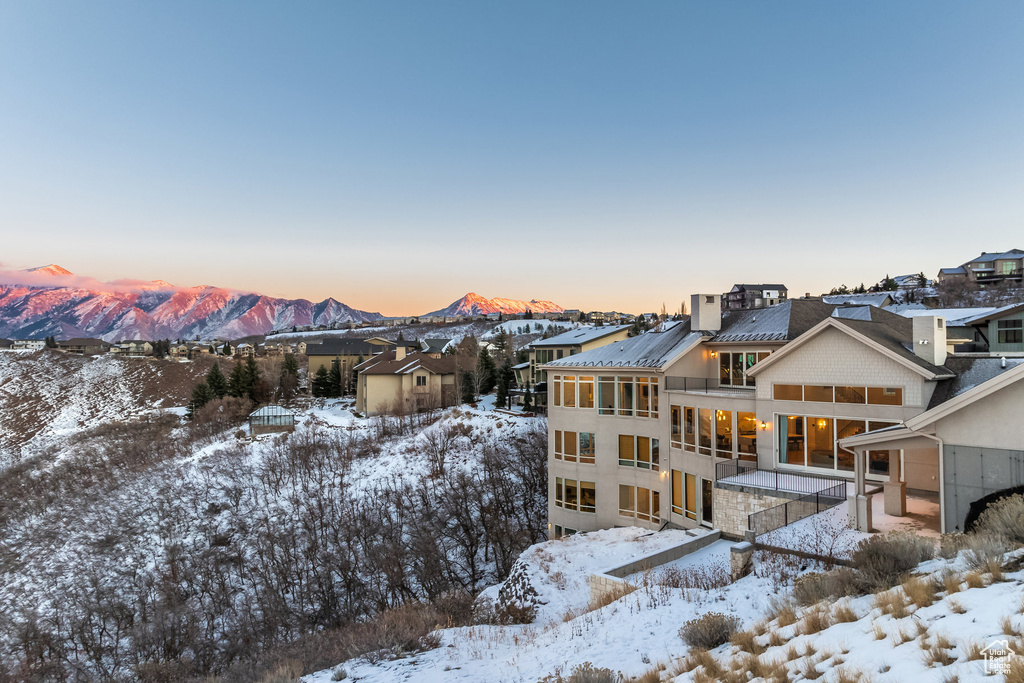 Snow covered house featuring a mountain view and a sunroom