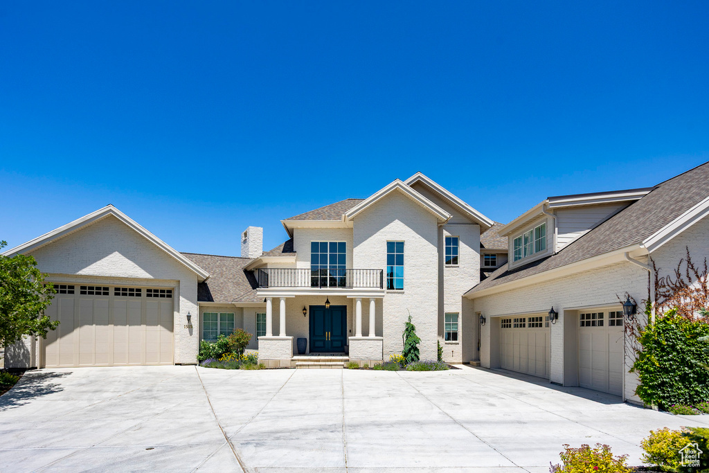 View of front of house featuring driveway, covered porch, an attached garage, and brick siding