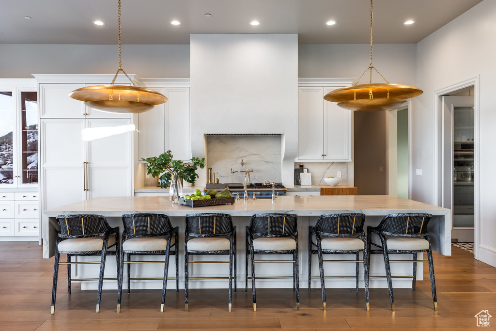 Kitchen featuring pendant lighting, a kitchen breakfast bar, a spacious island, and white cabinetry