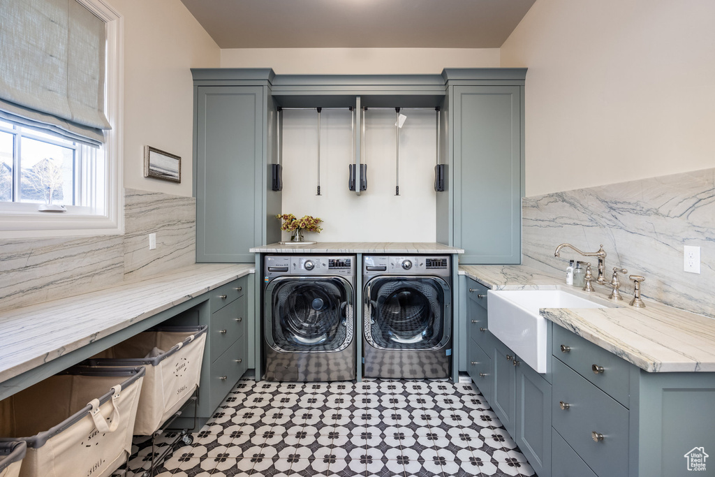 Clothes washing area featuring cabinets, sink, and washer and dryer